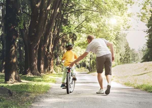 Father help his son ride a bicycle